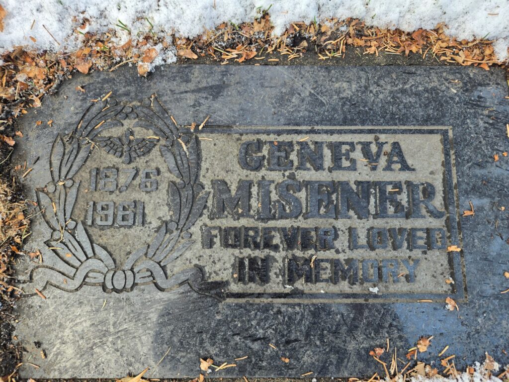 A flat gravestone reads “1876-1961 – Geneva Misener – Forever Loved in Memory.”