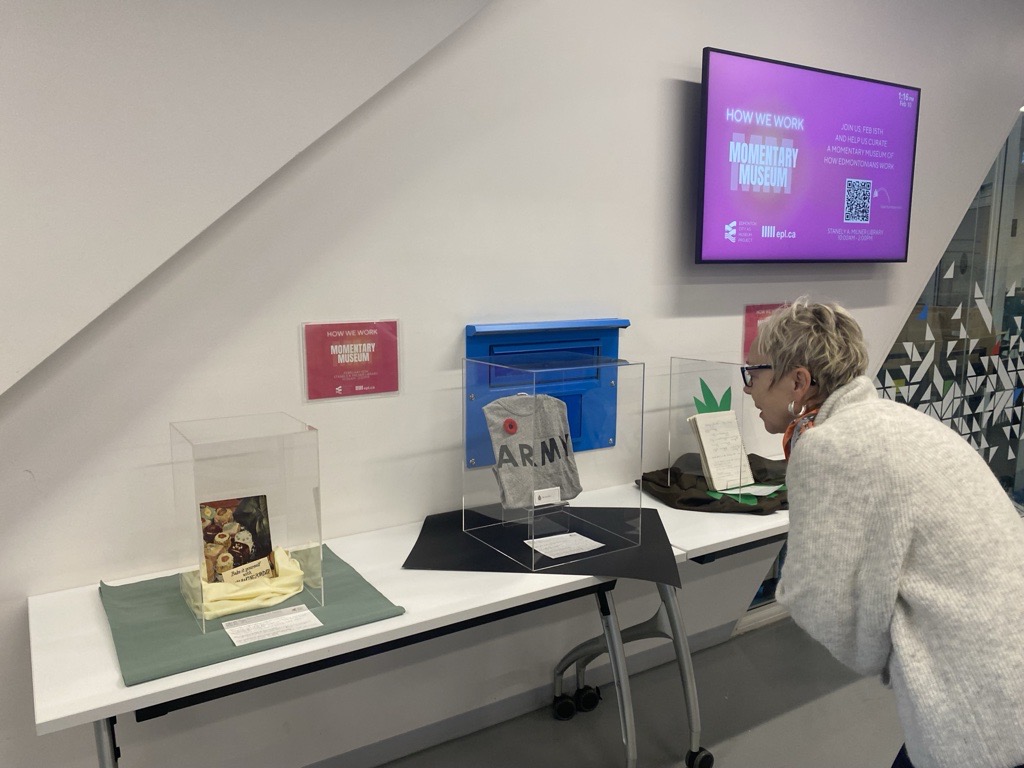 A photo of a woman leaning in to look at a pop-up display of an army t-shirt