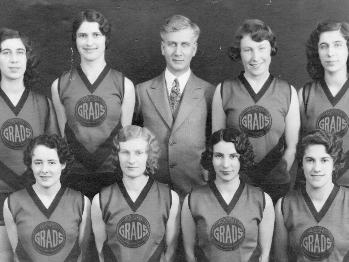 Eight players pose for the camera in their jerseys, with their coach and a basketball.