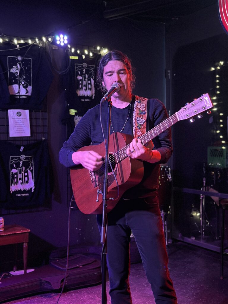 A man sings and plays a guitar in a local bar.