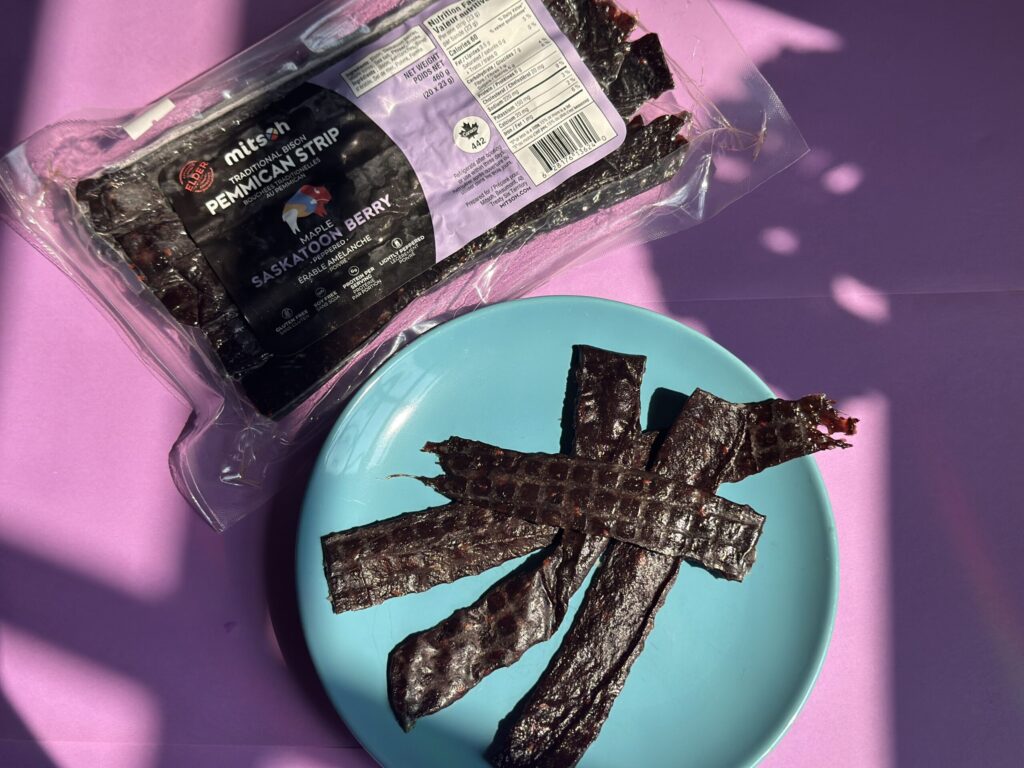 A package of pemmican strips beside a plate of four pieces of pemmican.