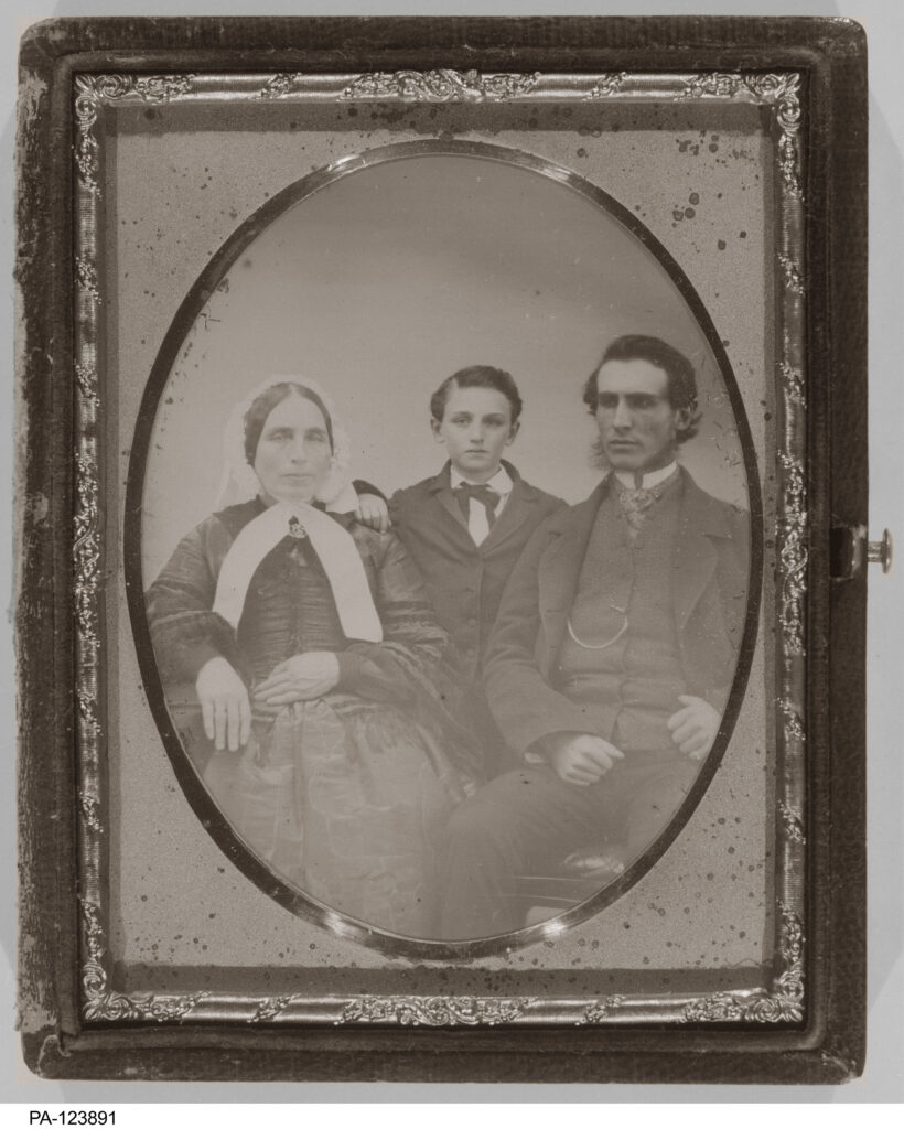 A daguerrotype of an older woman, a boy, and a young man.