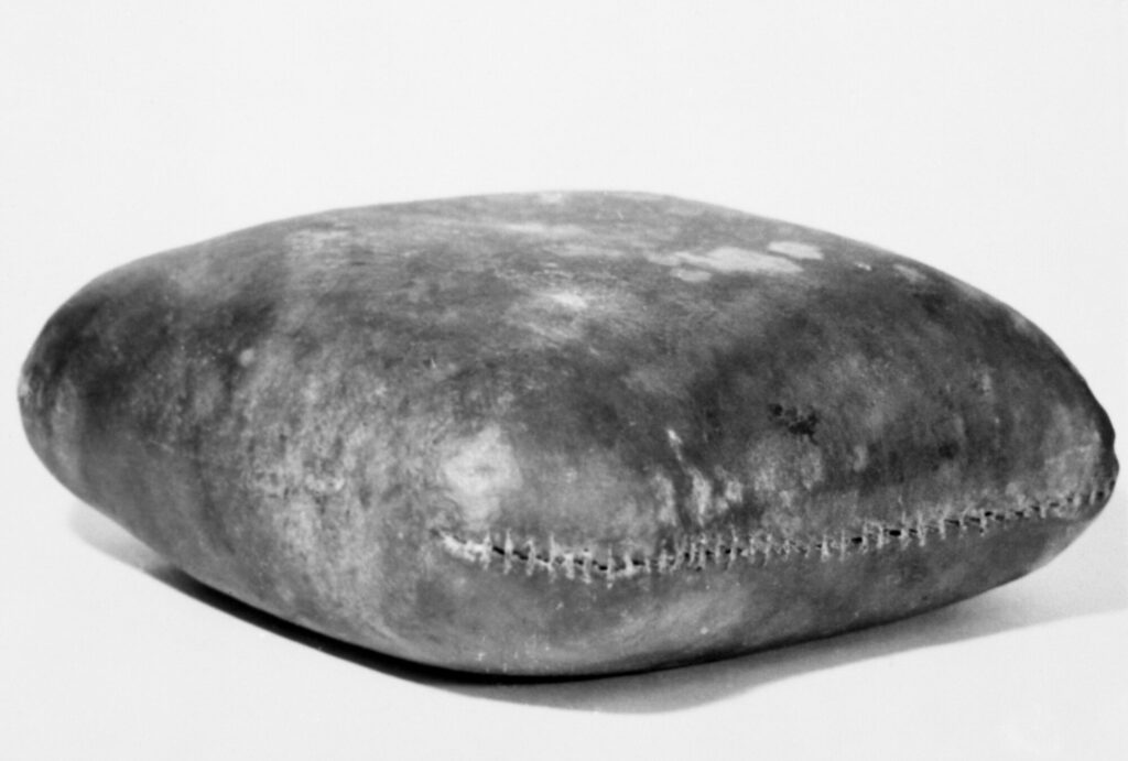 A photograph of a full rectangular hide bag, sewn up.