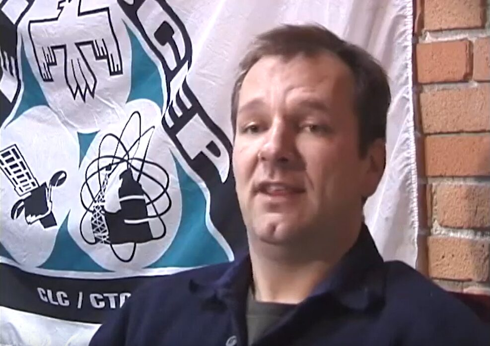 A man sitting in front of a brick wall with the CEP union flag.